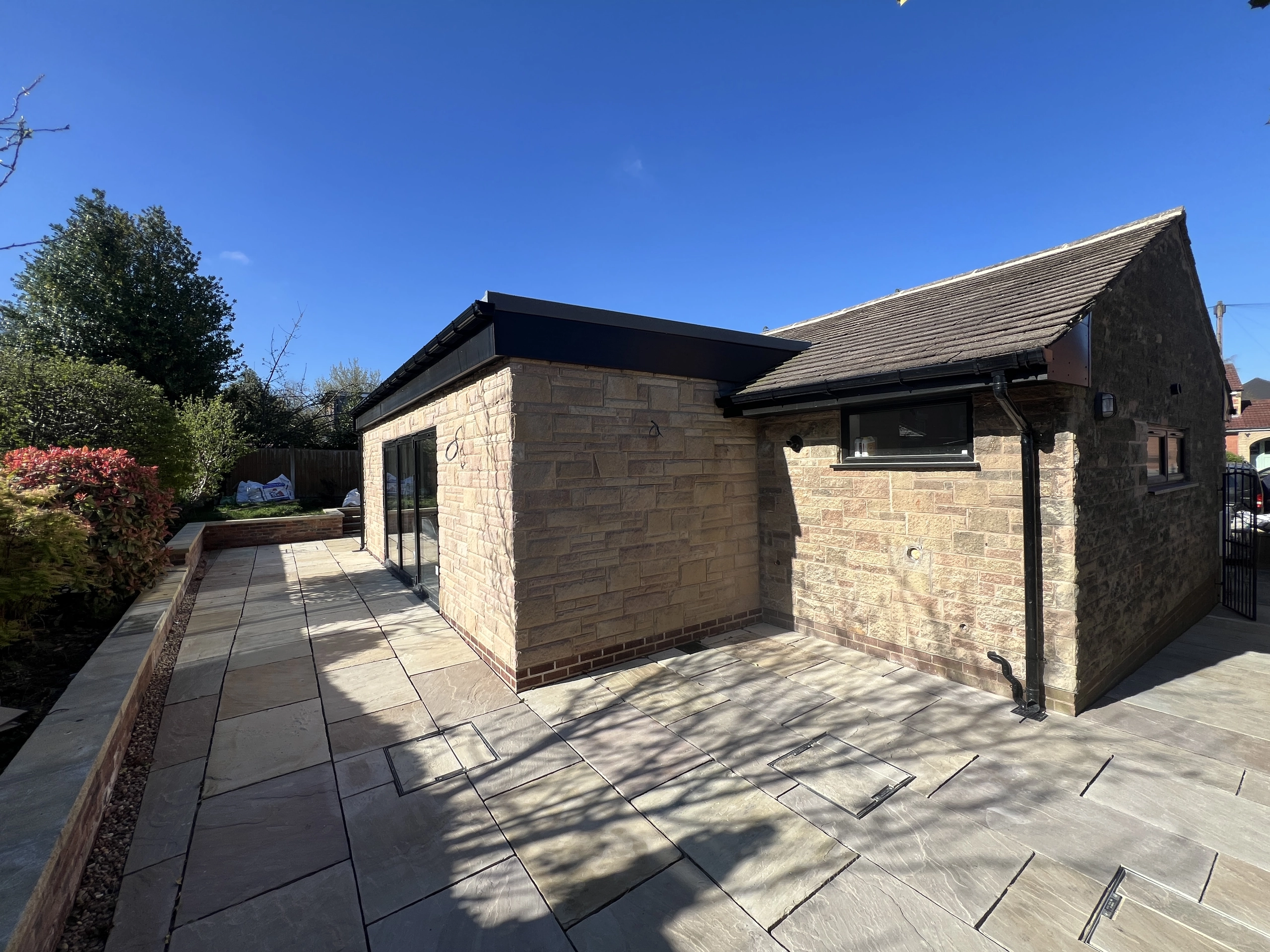 a building with a roof and a brick wall at Havendale Accessible Holiday Cottage