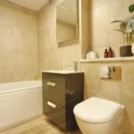 a bathroom with a toilet, sink, and mirror at Havendale Accessible Holiday Cottage