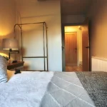 a bed with a white comforter and a lamp at Havendale Accessible Holiday Cottage