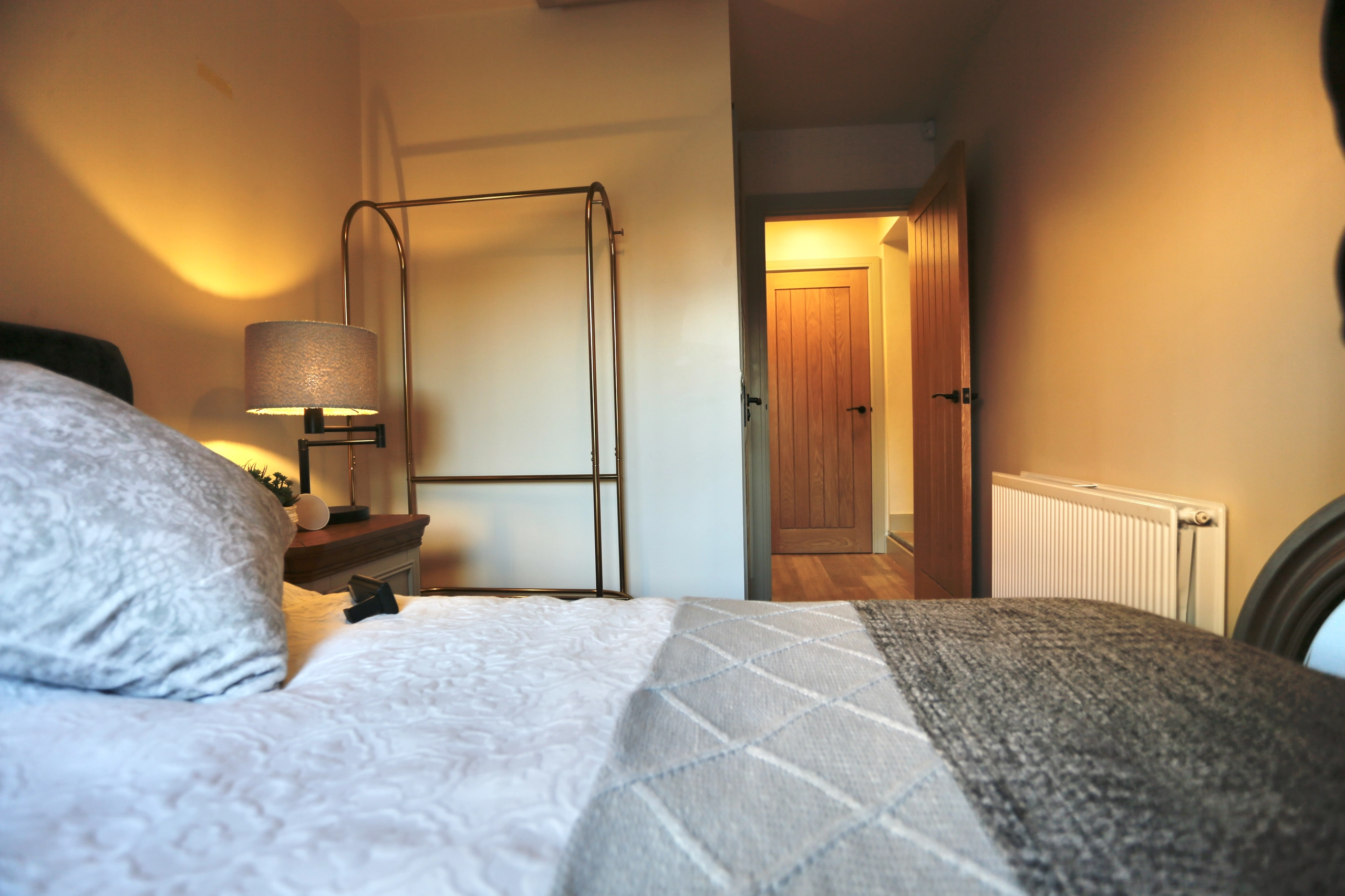 a bed with a white comforter and a lamp at Havendale Accessible Holiday Cottage