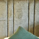 a cat sitting on a bed with a pillow at Havendale Accessible Holiday Cottage