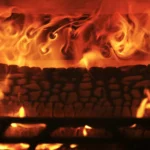 a fire burning in a fireplace with rocks and flames at Havendale Accessible Holiday Cottage