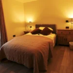 a bed with a brown comforter and a brown pillow at Havendale Accessible Holiday Cottage
