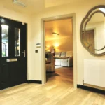a hallway with a mirror and a black door at Havendale Accessible Holiday Cottage