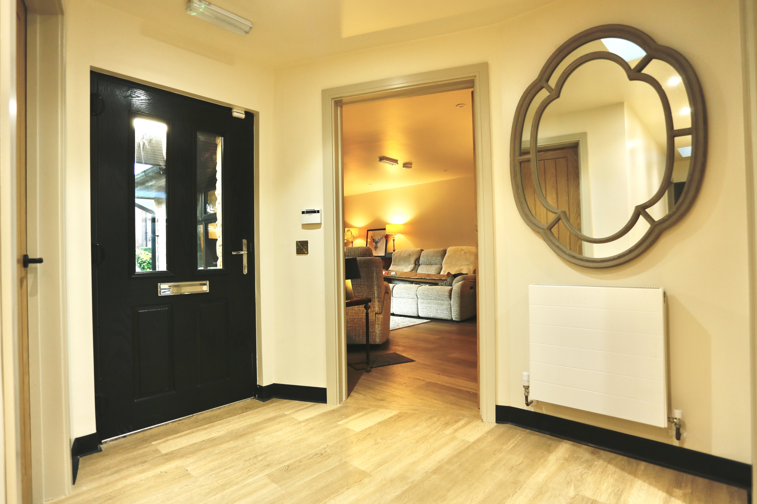 a hallway with a mirror and a black door at Havendale Accessible Holiday Cottage