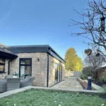 a house with a tree in the yard at Havendale Accessible Holiday Cottage