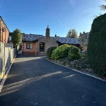a driveway with a fence and a house in the background at Havendale Accessible Holiday Cottage