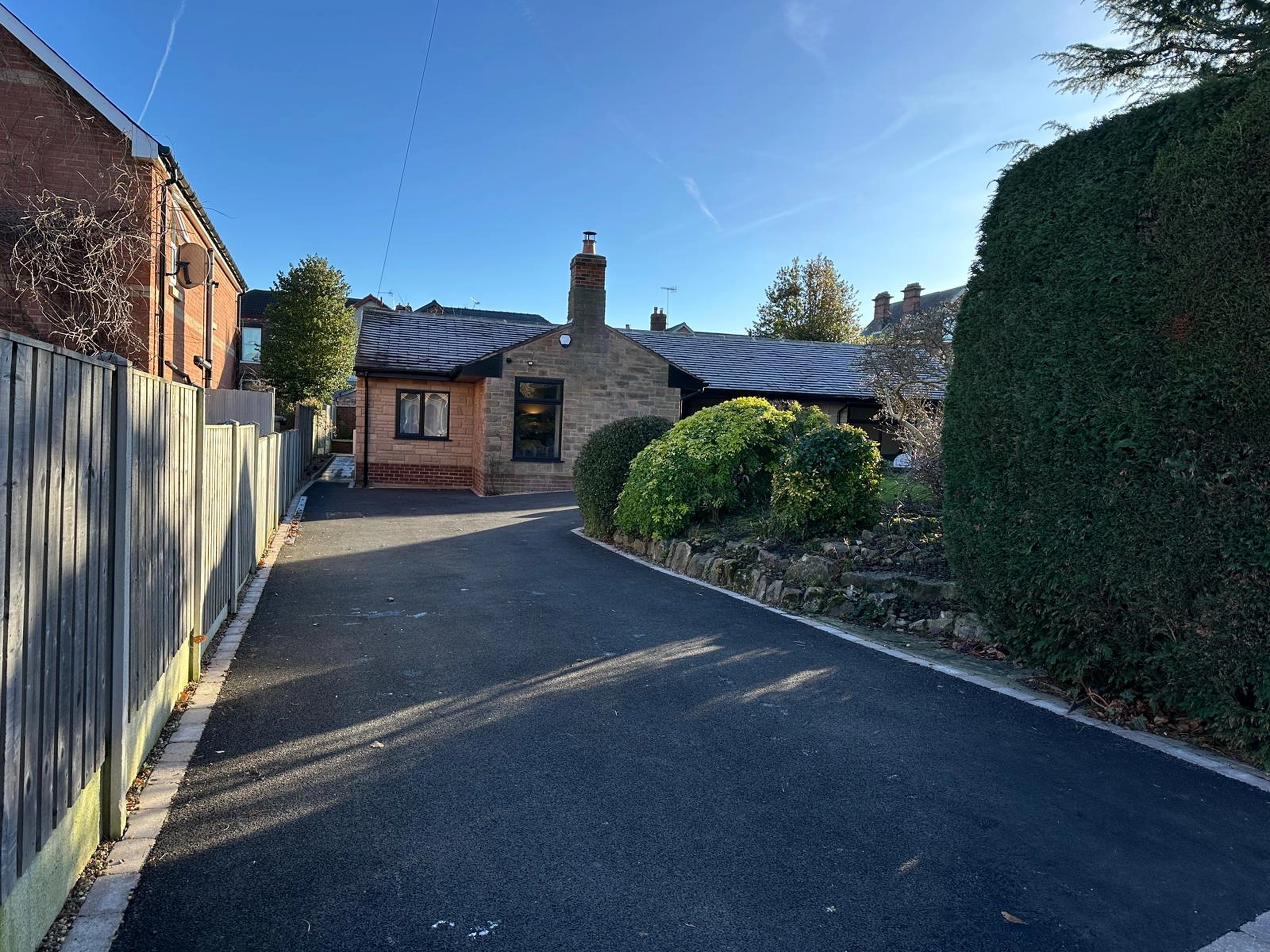 a driveway with a fence and a house in the background at Havendale Accessible Holiday Cottage