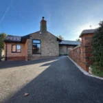 a brick house with a driveway and a gate at Havendale Accessible Holiday Cottage