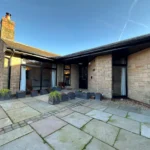 a patio with a stone patio and a brick wall at Havendale Accessible Holiday Cottage