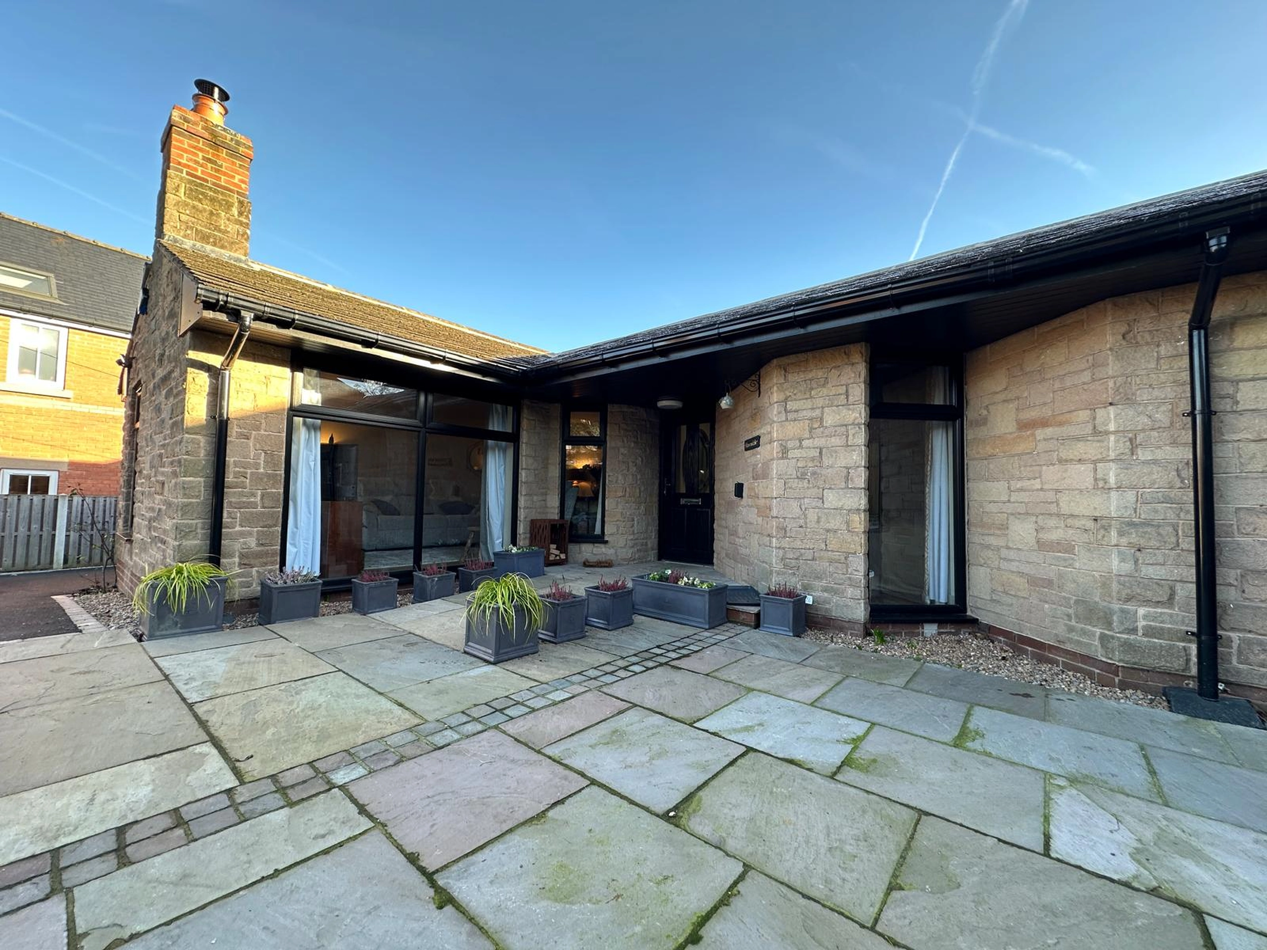 a patio with a stone patio and a brick wall at Havendale Accessible Holiday Cottage