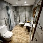 Accessible bathroom at Havendale. There is a luxury family bathroom located off the main corridor. This bathroom is not wheelchair accessible. It features a full-size bath (1800mm x 800mm) with a shower over, and a portable bath lift is available on request. The bathroom also includes a vanity wash basin, wall-hung toilet and illuminated mirror. The floor is finished with non-slip tiles.