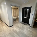 a hallway with a black door and a white wall at Havendale Accessible Holiday Cottage