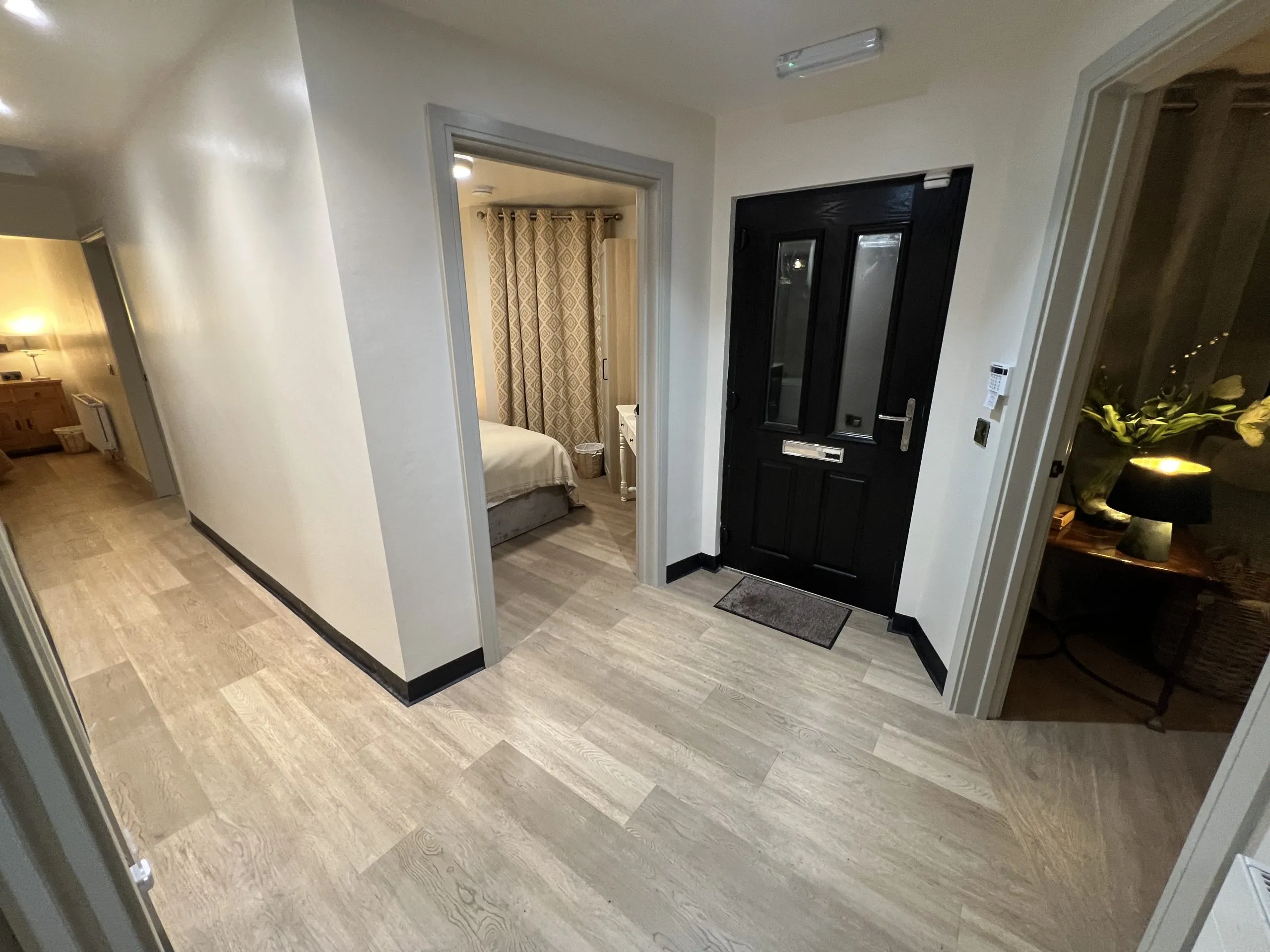 a hallway with a black door and a white wall at Havendale Accessible Holiday Cottage