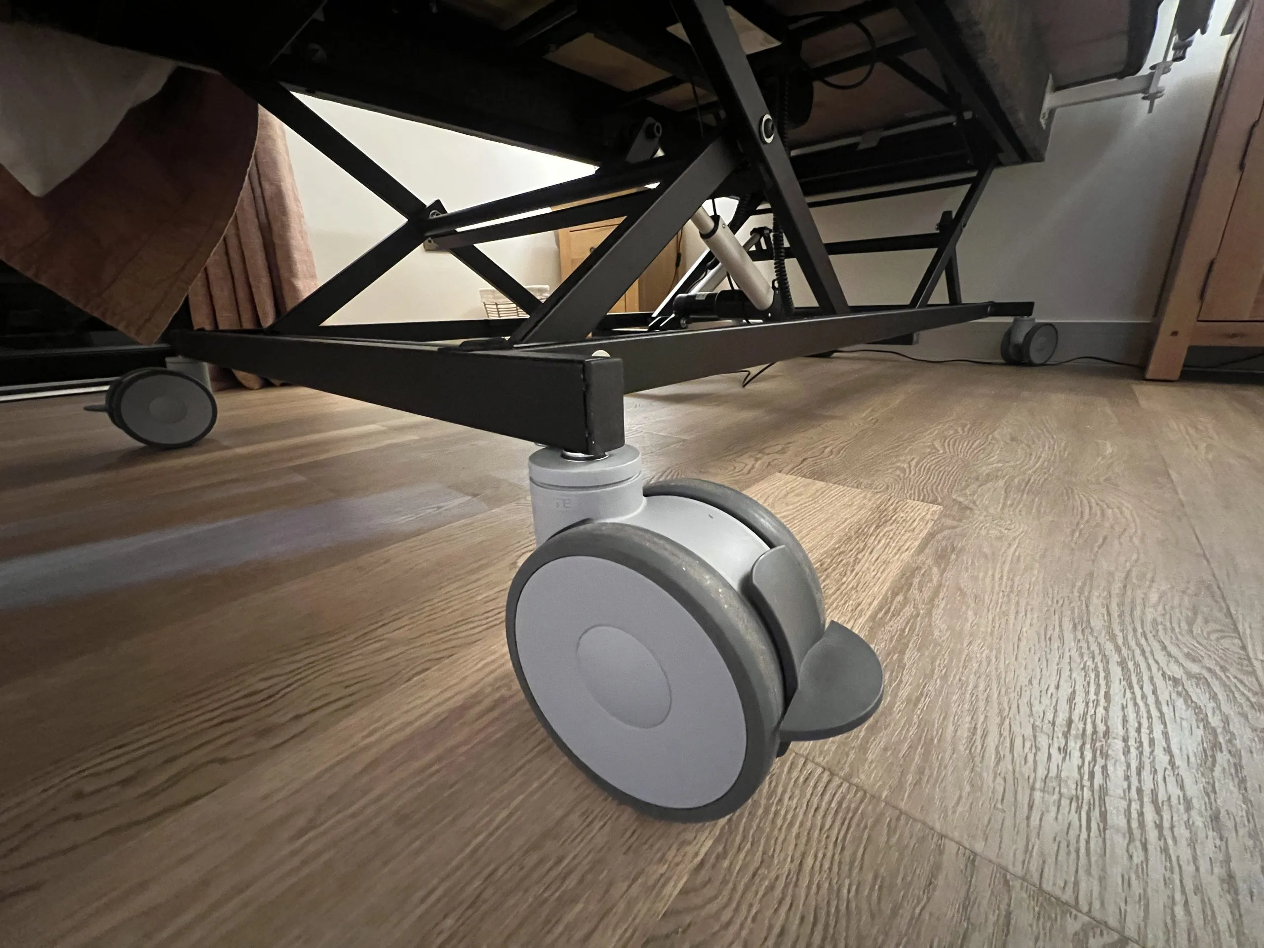 a wooden floor with a black roller under the bed at Havendale Accessible Holiday Cottage