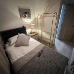 a bed with a blanket and a lamp at Havendale Accessible Holiday Cottage