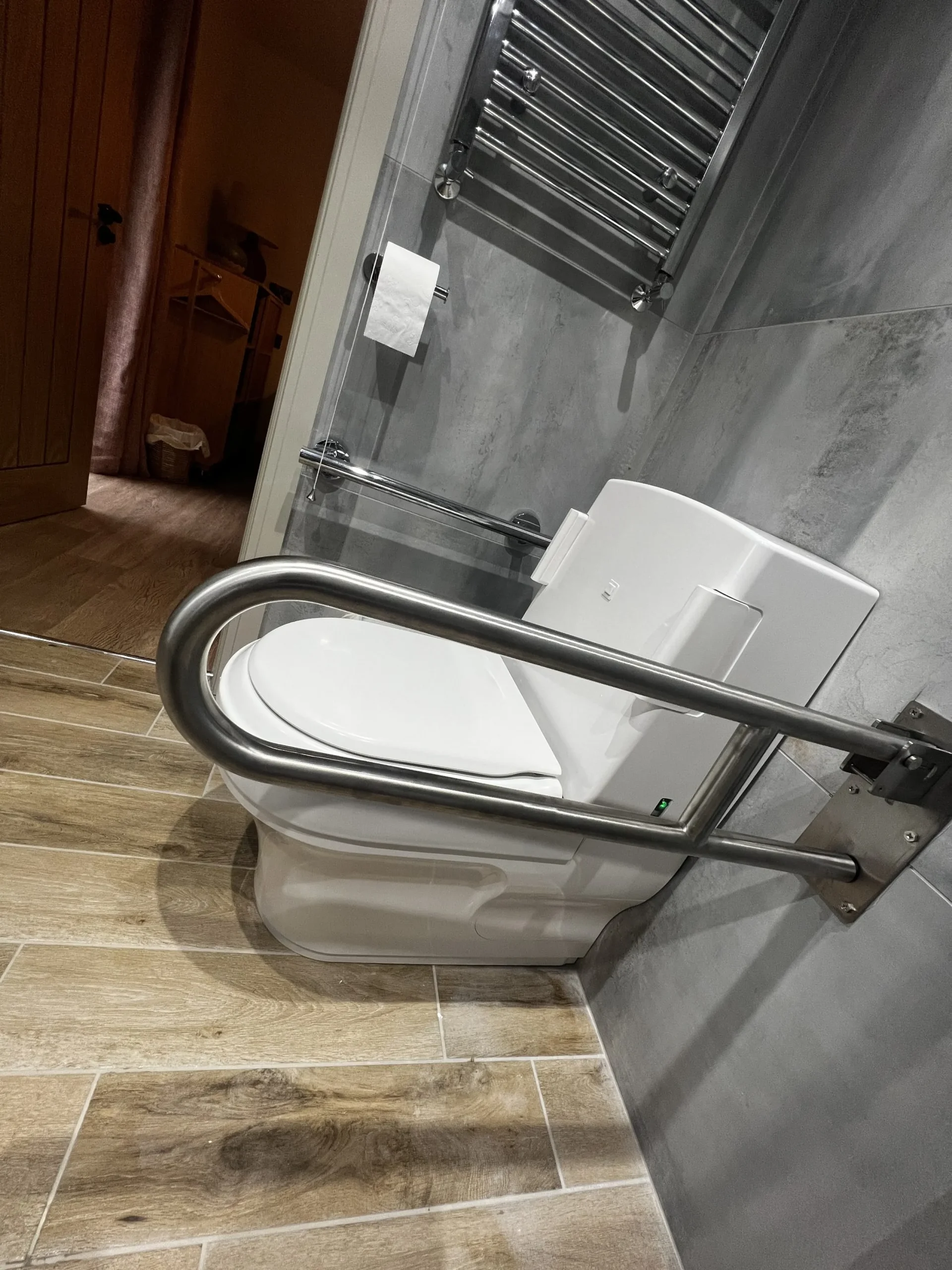 a toilet with a metal support rail in a bathroom at Havendale Accessible Holiday Cottage