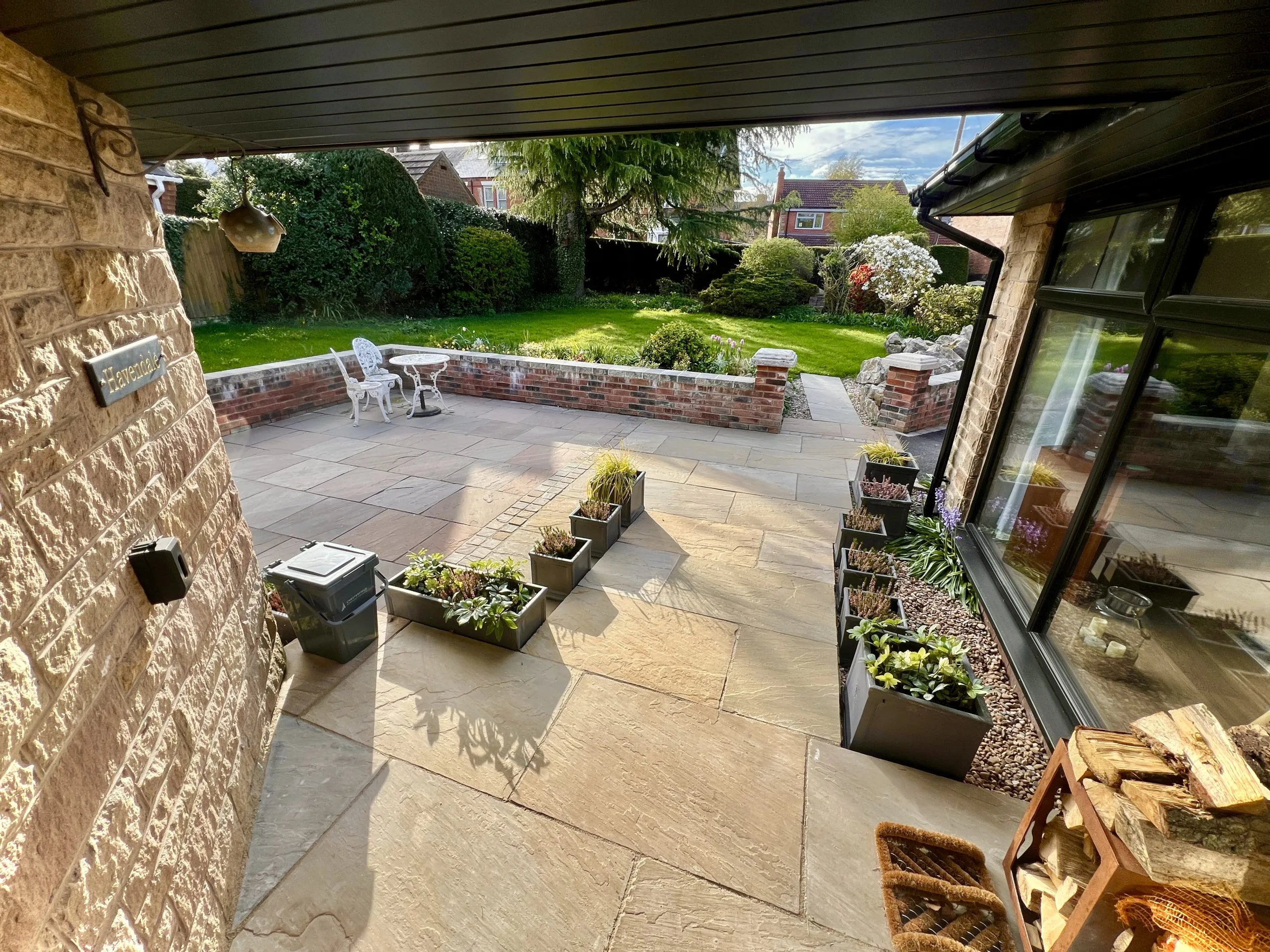 a patio with a stone wall and the garden at Havendale Accessible Holiday Cottage