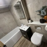 a bathroom with a toilet, sink and mirror at Havendale Accessible Holiday Cottage